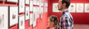 man and daughter at an art exhibit looking at prices